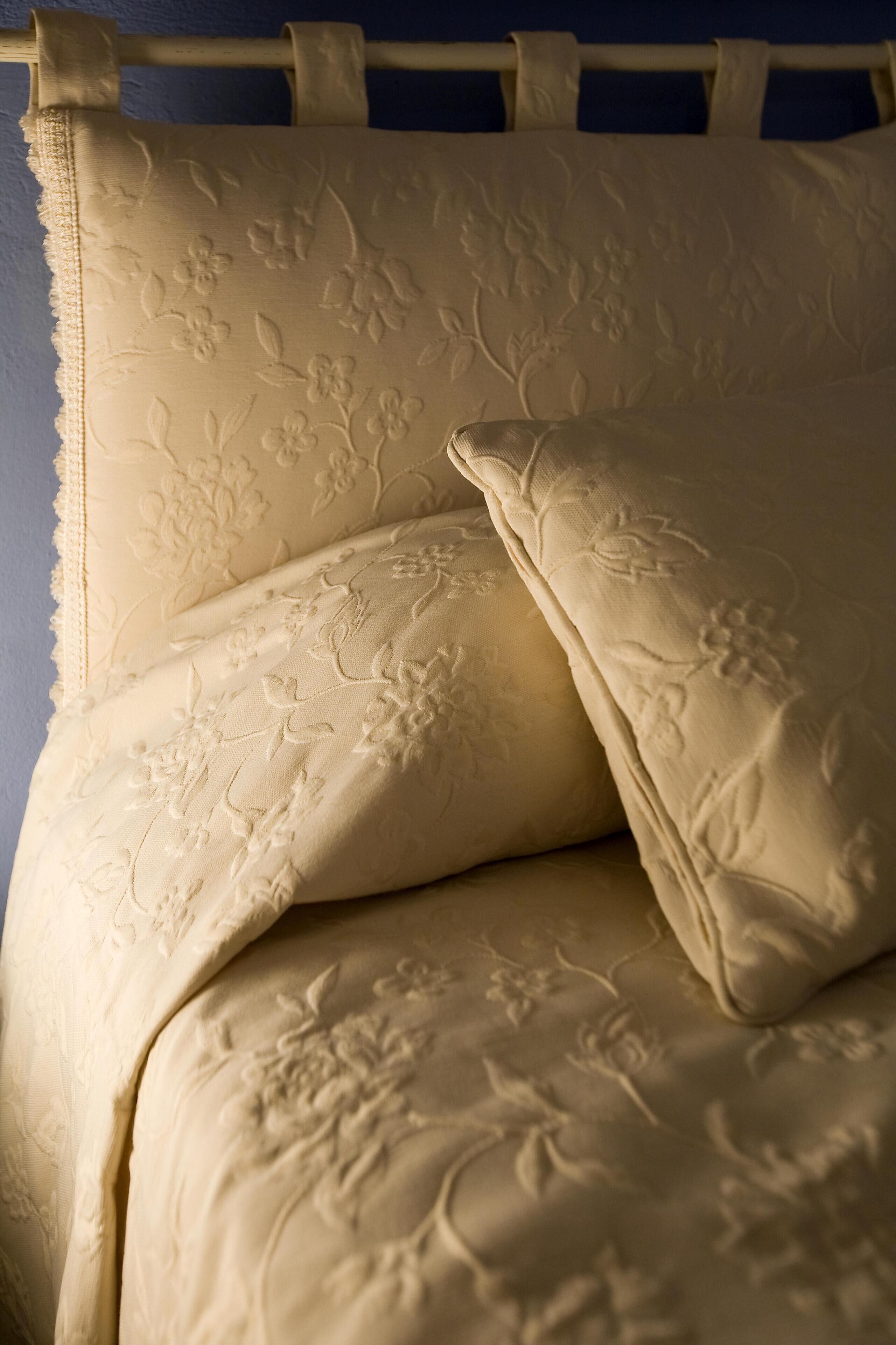 Una cama con ropa de cama de estampado floral y un cabecero.