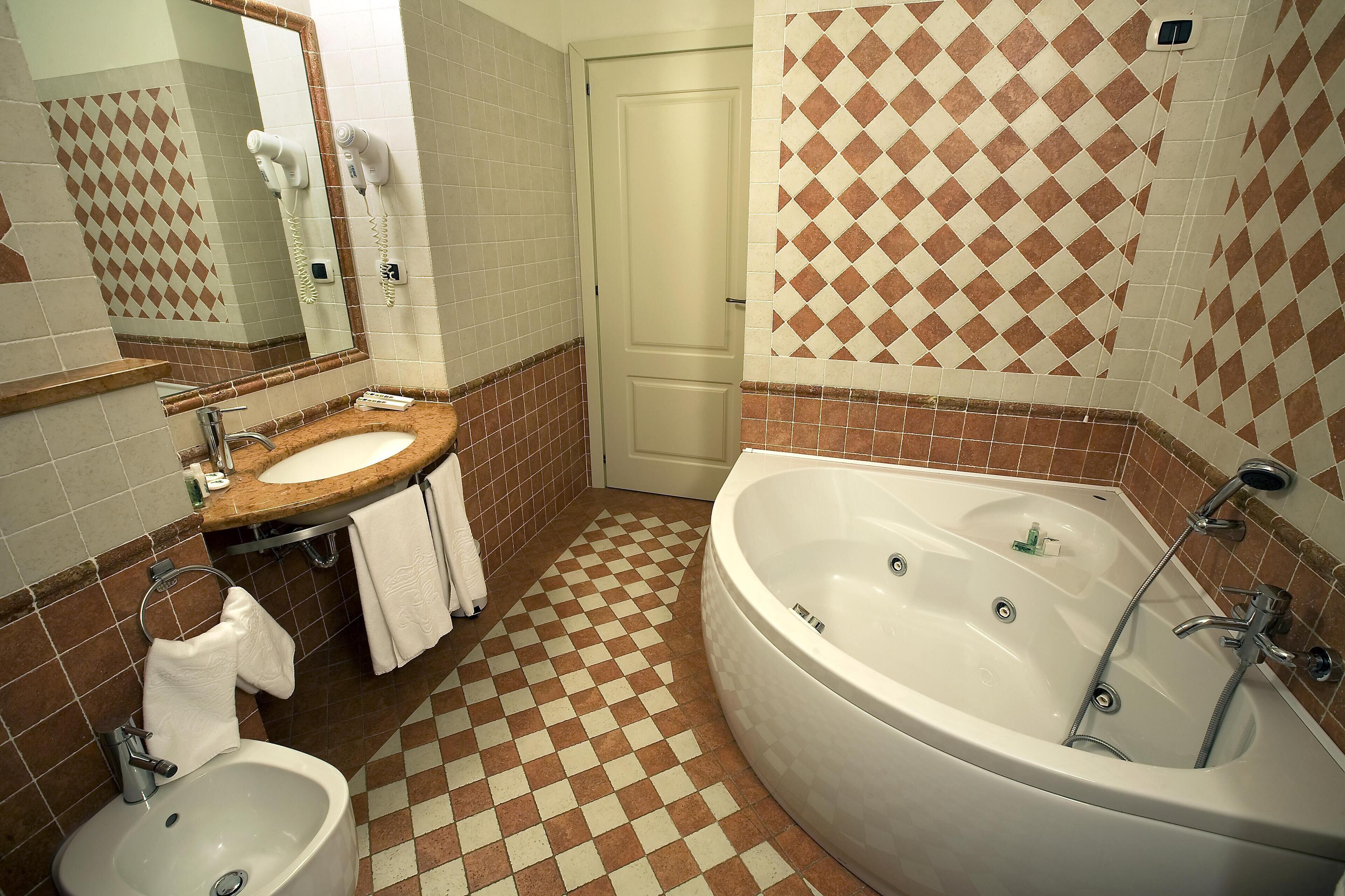 Un baño con suelo a cuadros, un lavabo, un bidé, una bañera y un espejo.