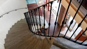 Eine Wendeltreppe mit schwarzer Geländer, transparente Pendelleuchten und eine Backsteinwand mit italienischem Text.