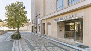 A hotel entrance with a tiled pathway, a street lamp, and a tree. - Divani Palace Larissa (Larissa)