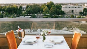 A table set for two with a view of a cityscape and mountains in the background. - Divani Palace Larissa (Larissa)
