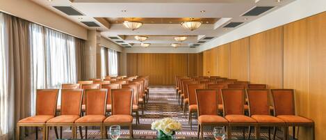 A conference room with rows of chairs, a long table, and a floral centerpiece.