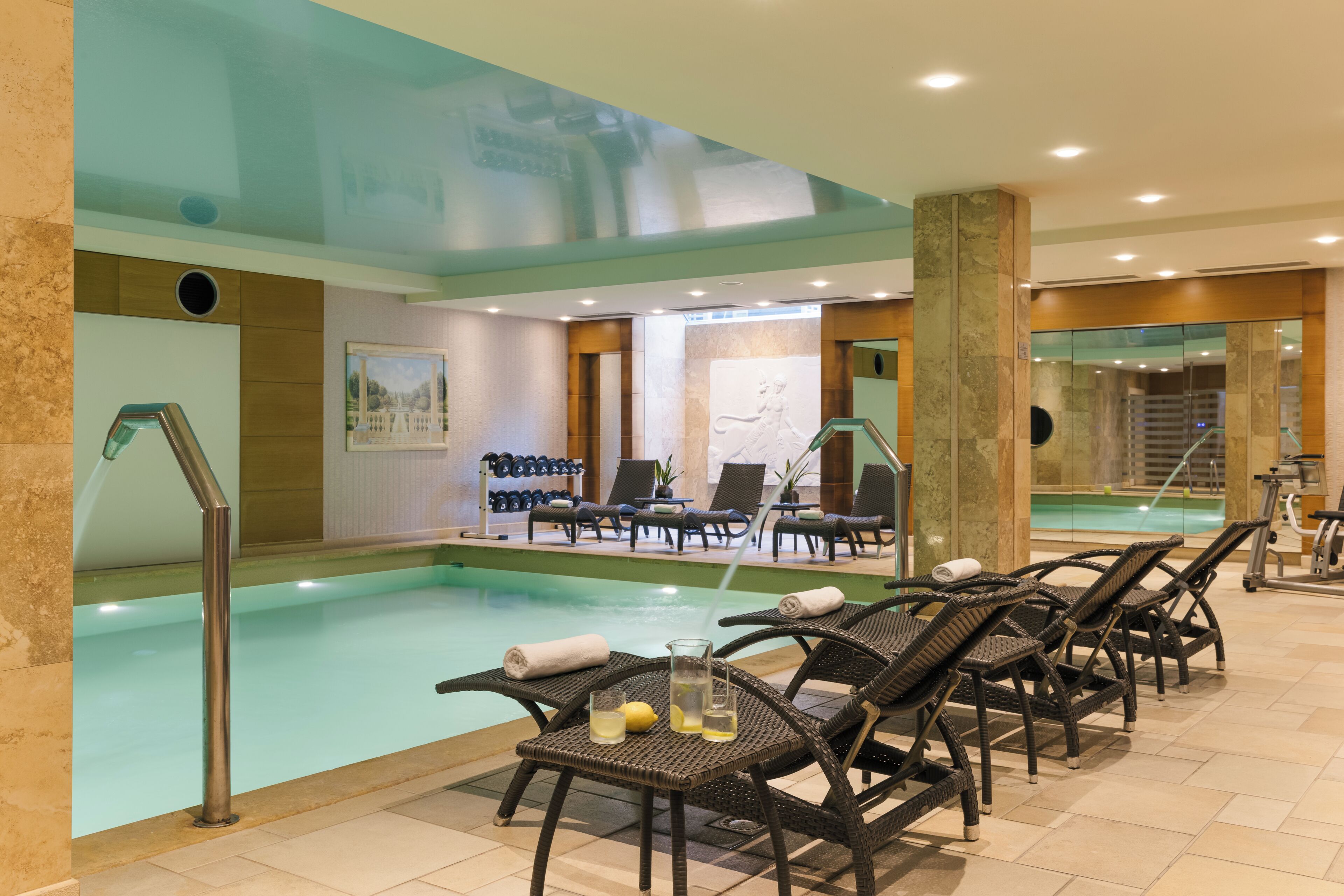 A pool area with lounge chairs and a table with drinks.
