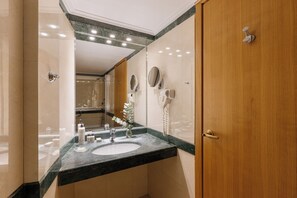 A modern bathroom with a large mirror, a sink, and a hairdryer.