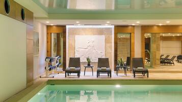 Un espace aménagé au bord de la piscine, avec des chaises longues et une sculpture fixée au mur.