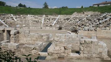 An ancient amphitheater with stone seating and a central stage area.