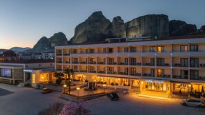Un hotel con varios pisos, asientos al aire libre y vistas a montañas escarpadas.