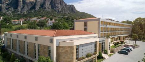 A modern building with a parking lot and a mountain in the background.