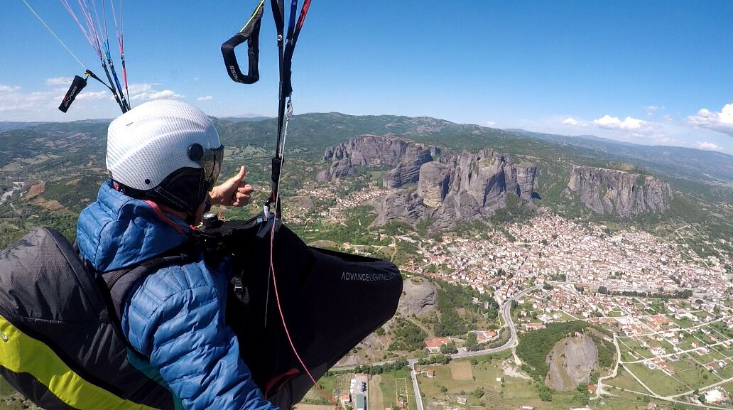Une personne vêtue d’une veste bleue et d’un casque, se préparant à atterrir avec un parapente.