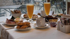 A breakfast table with various dishes and a glass of orange juice, overlooking a mountainous landscape.