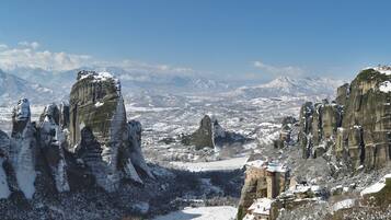 A mountainous landscape with rock formations and a building with snow-covered roofs.