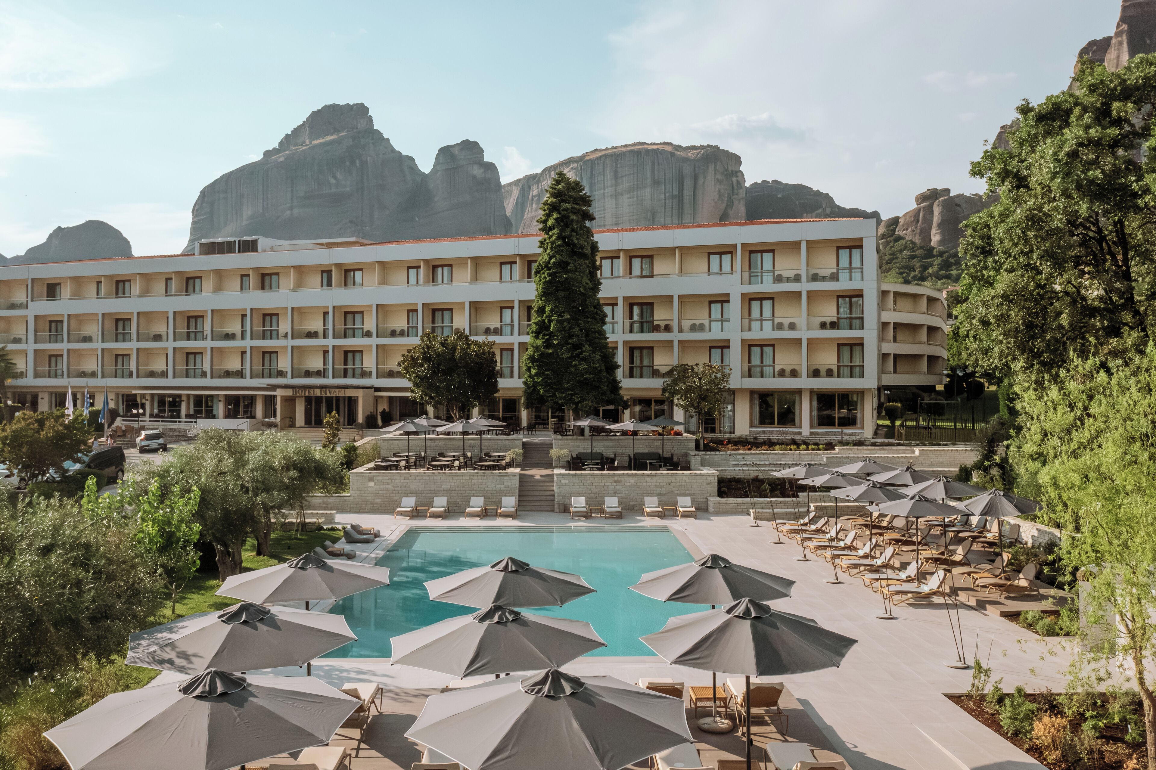 Un hotel con piscina, sillones de descanso y sombrillas.