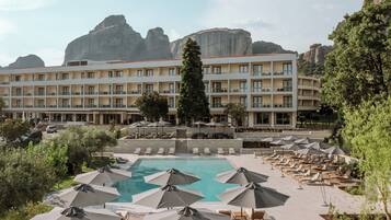 Un hotel con piscina, sillones de descanso y sombrillas.