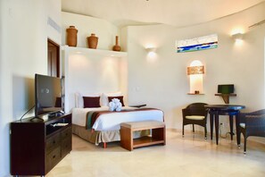 A hotel room with a bed, television, dresser, and a small dining area with chairs and a table.