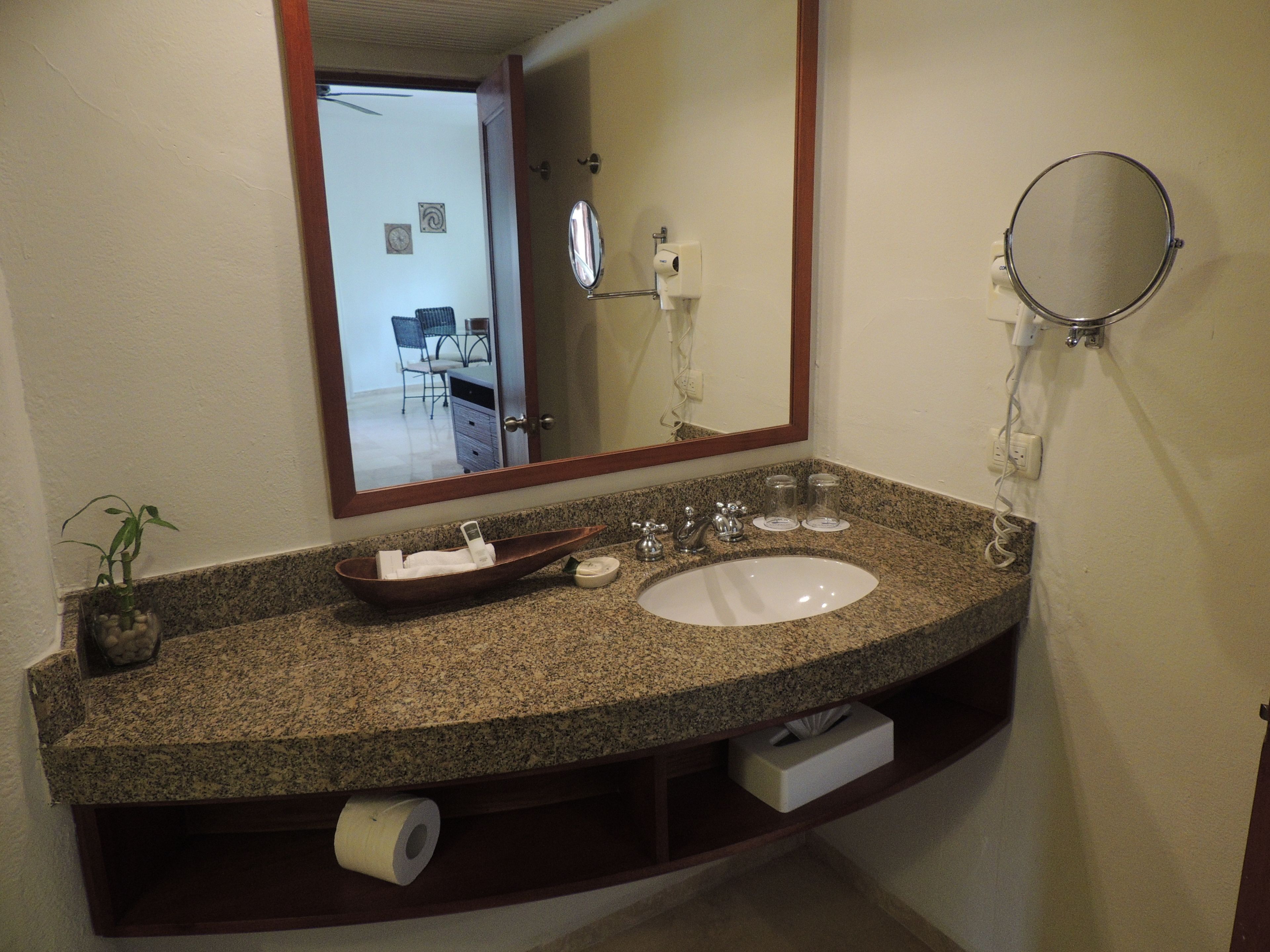 A bathroom with a granite countertop, a white sink, a mirror, and a towel rack.