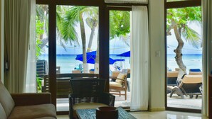 Habitación con vista a la playa, que incluye un sofá, una silla de mimbre y una mesa.