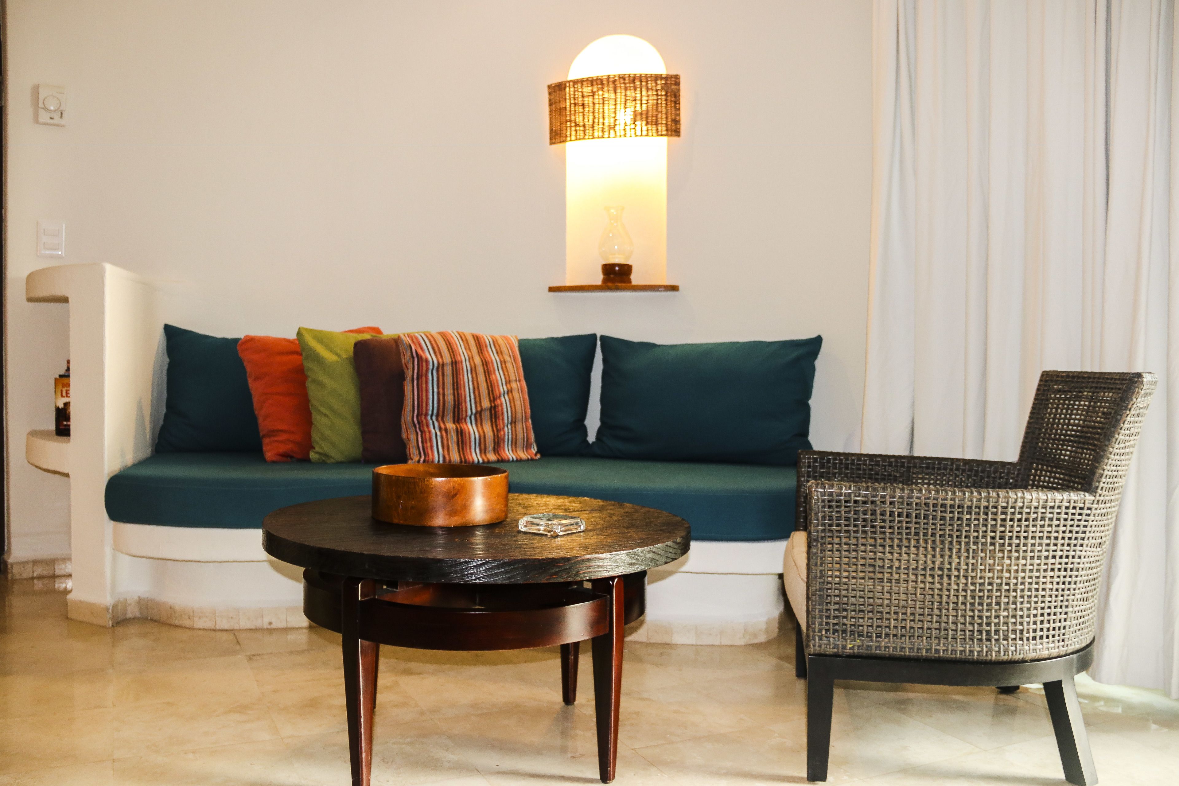 A modern living room with a sofa, a round coffee table, and a wicker chair.