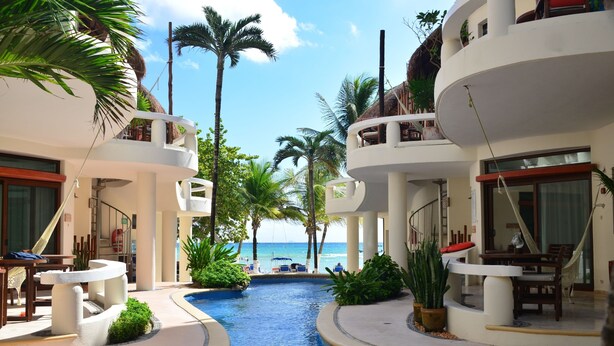 Un resort con piscina, palmeras y vista al océano.