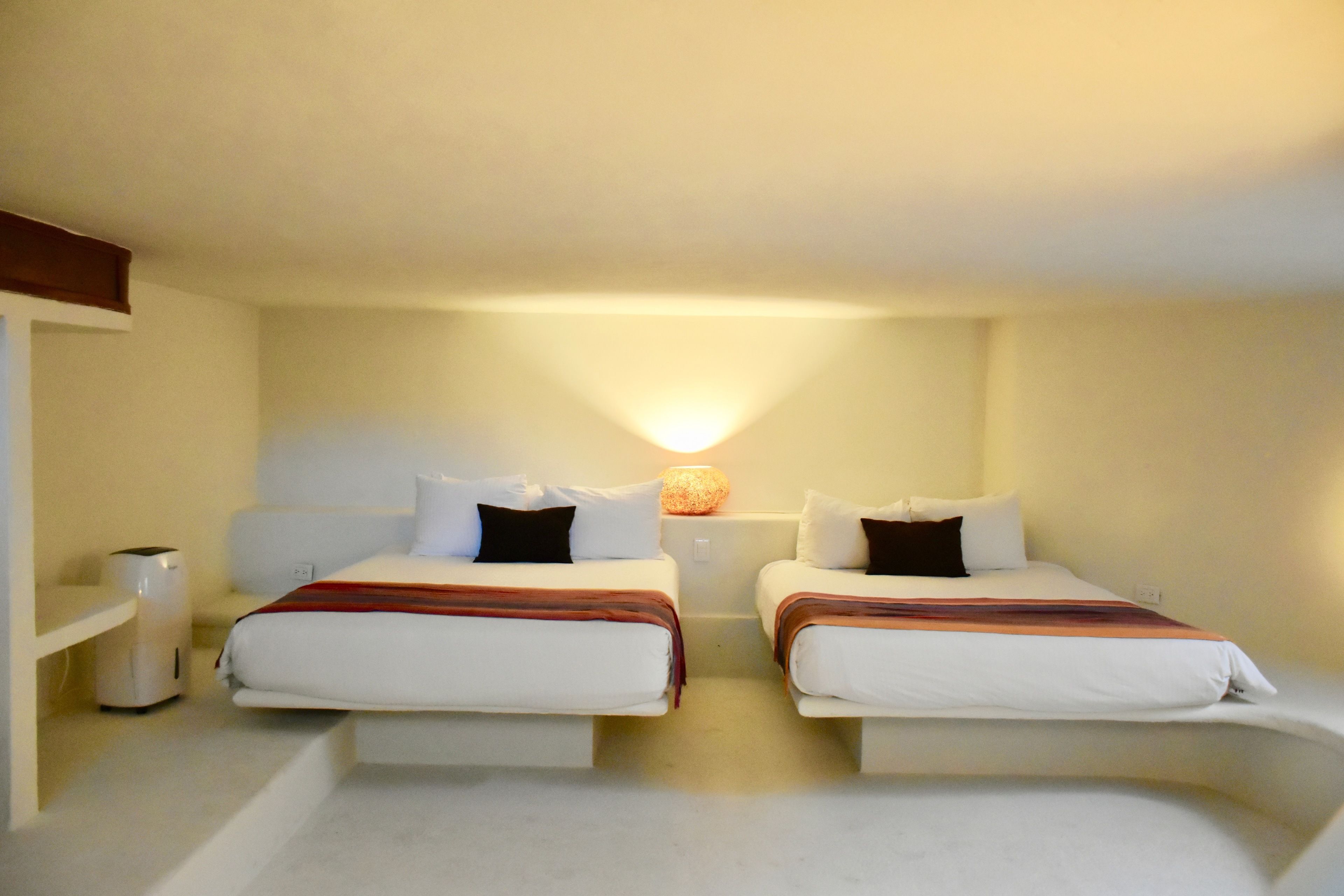 Ein Hotelzimmer mit zwei Betten, einem Nachttisch mit Lampe und einem Regal mit Heizung.