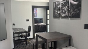 Un espace repas moderne avec une table en bois foncé et des tabourets assortis, une moquette grise et une œuvre d’art accrochée au mur.