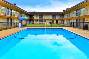 A swimming pool with a blue water surface, surrounded by a black fence.