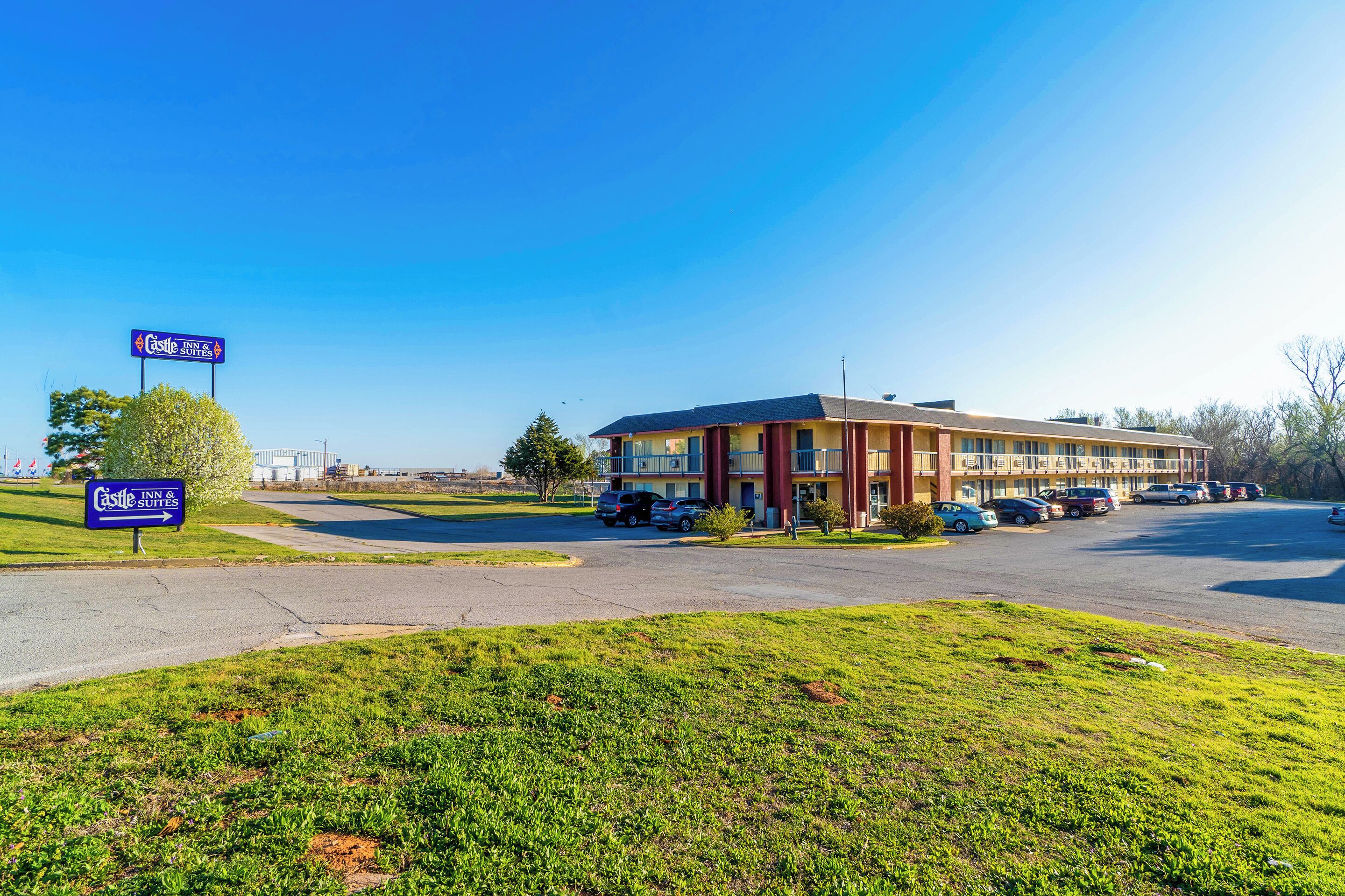 A Castle Inn & Suites building with a parking lot and a grassy area in front.