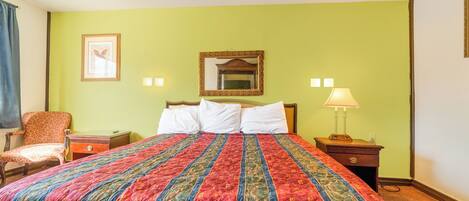 A hotel room with a large bed, a chair, a nightstand, and a lamp.