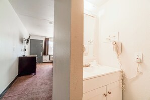 A hotel room with a white vanity, a mirror, a telephone, and a door leading to another room.