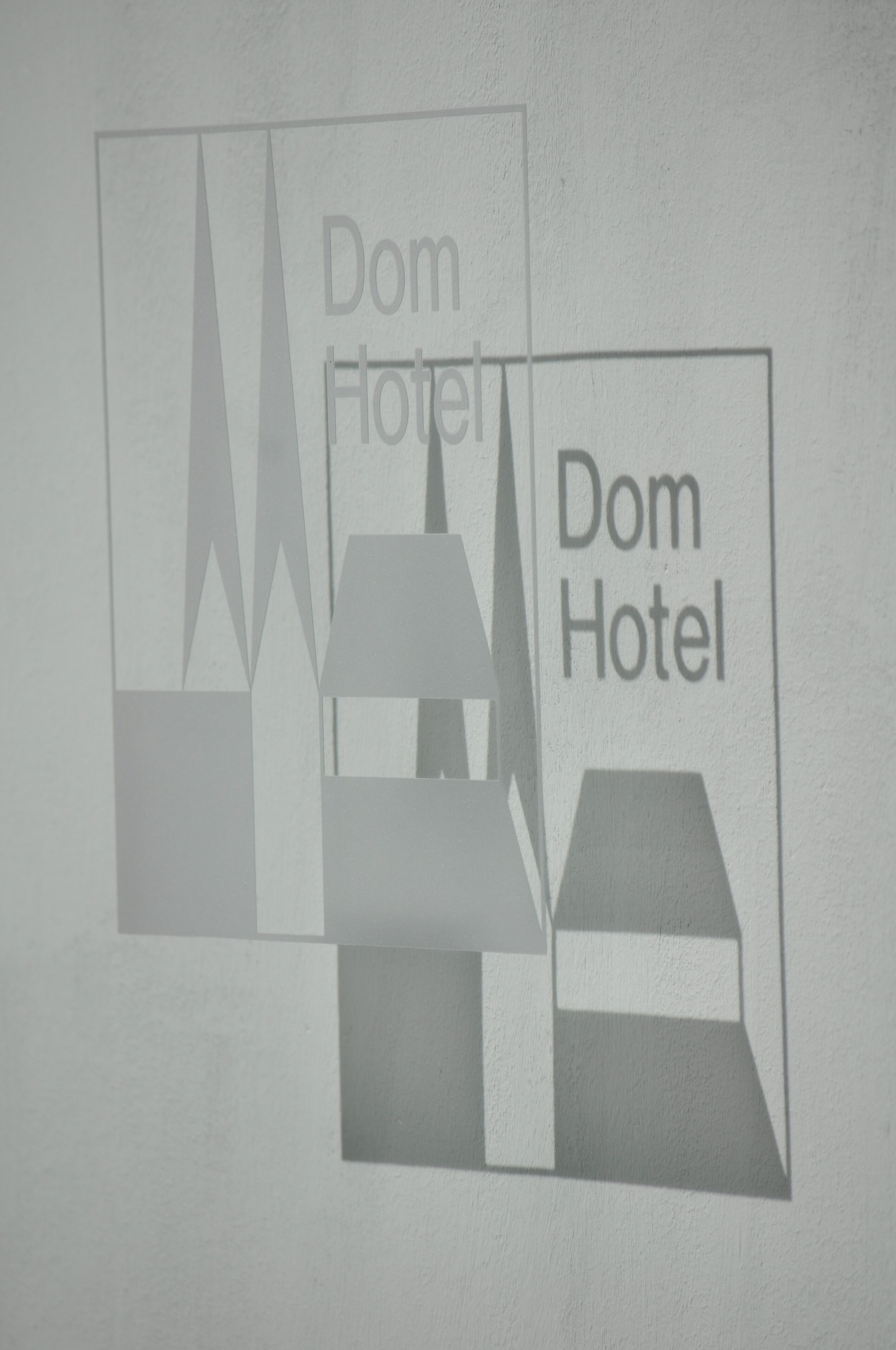 Een bord met de tekst 'Dom Hotel', herhaald in een gestileerd lettertype.