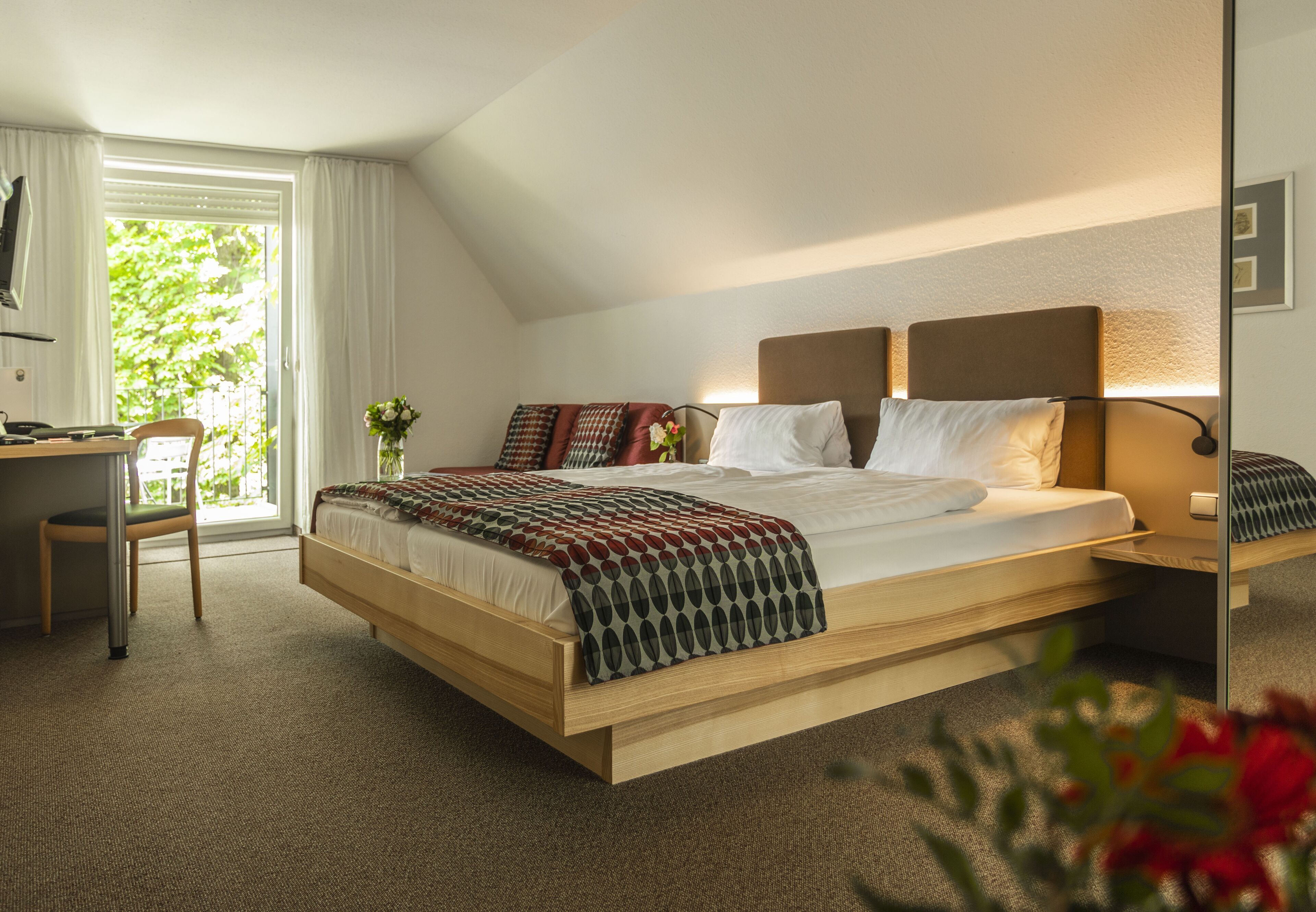 A modern bedroom with a large bed, a desk, and a chair.
