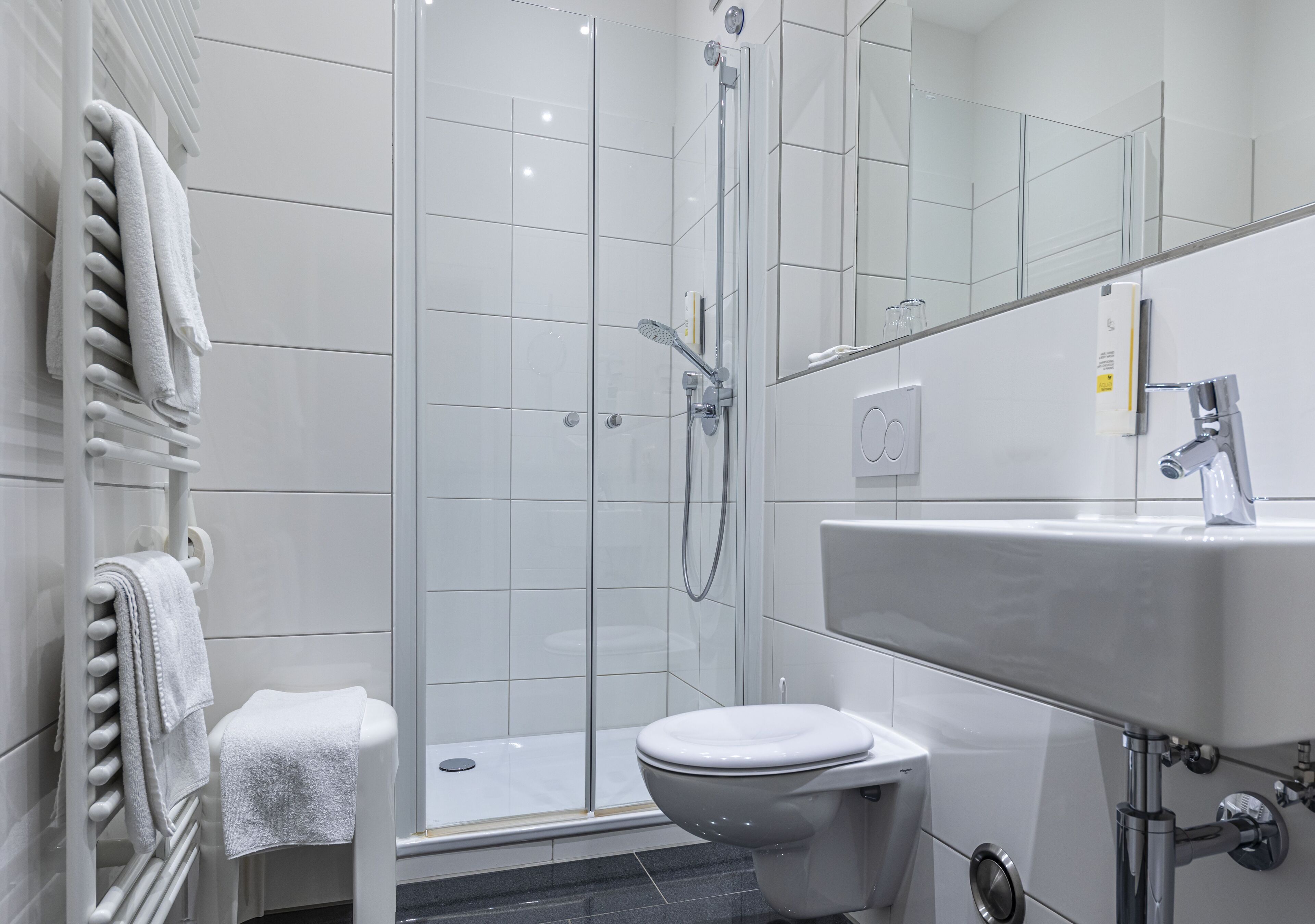 Un baño moderno con cabina de ducha de vidrio, inodoro blanco y lavabo con espejo.