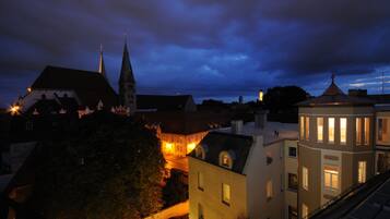Un pueblo histórico con una imponente torre de iglesia y un edificio bien iluminado con amplias ventanas.