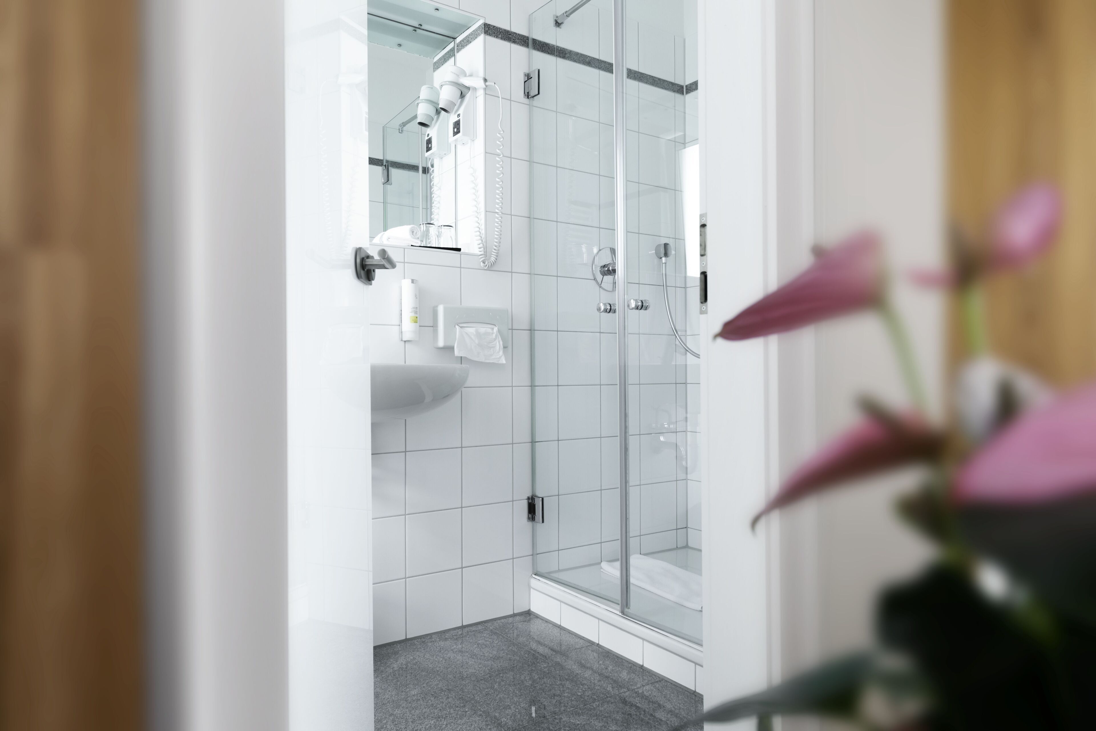 Un baño moderno con cabina de ducha de vidrio, un lavabo blanco y un espejo.