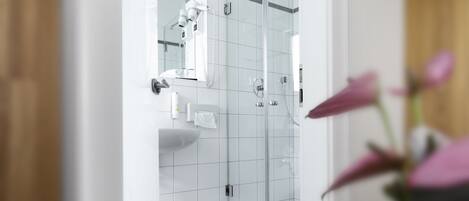 Un baño moderno con cabina de ducha de vidrio, un lavabo blanco y un espejo.