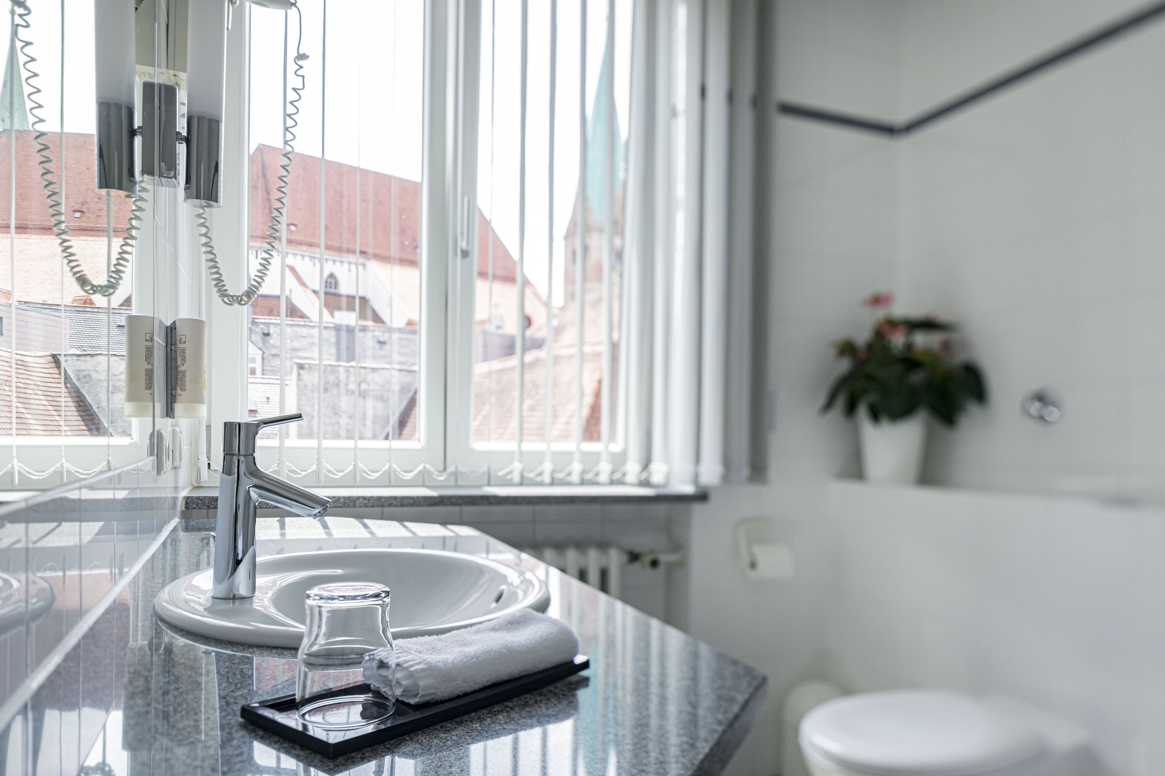 A modern bathroom with a granite countertop, a white sink, and a glass shower enclosure.