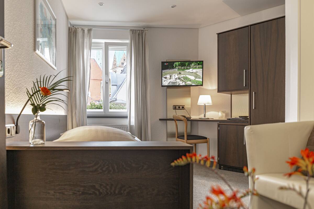 Una habitación de hotel con cama, escritorio, televisor y silla.