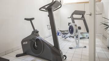 A home gym with a stationary bike, treadmill, and weights.