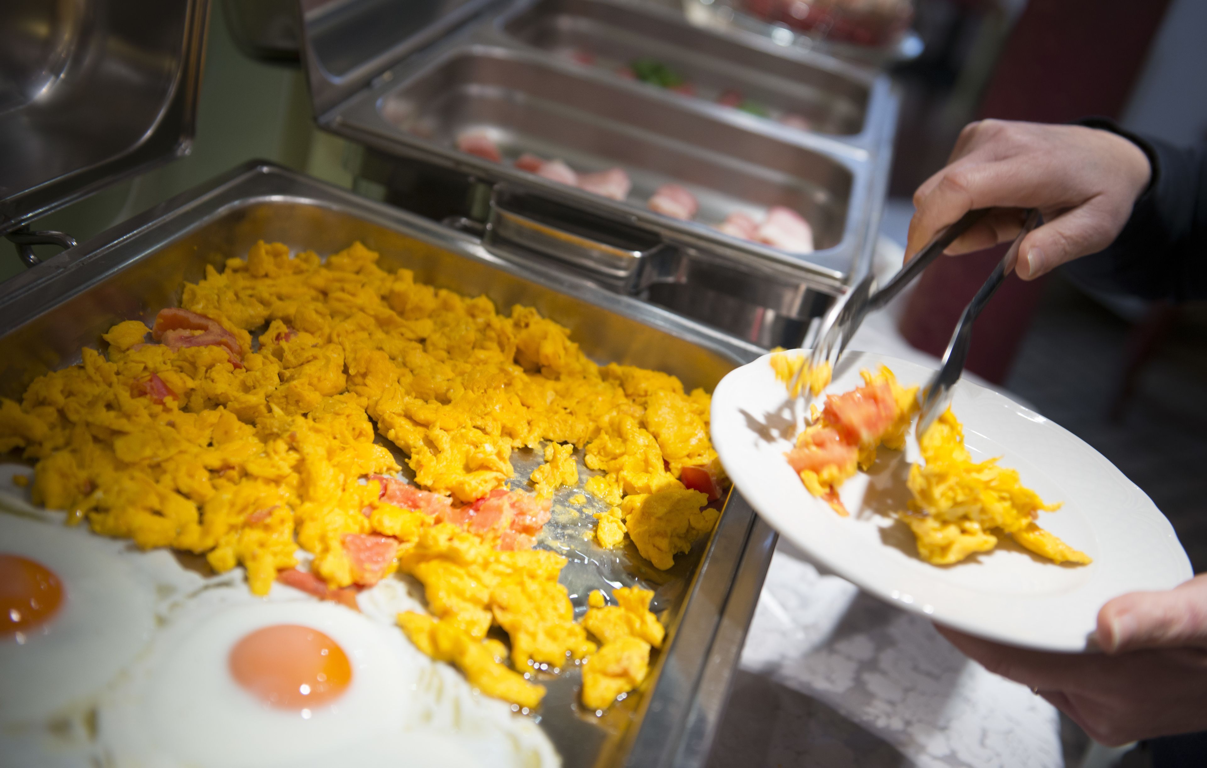 A buffet with scrambled eggs and a variety of other dishes.