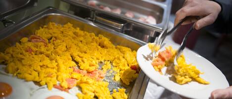 A buffet with scrambled eggs and a variety of other dishes.