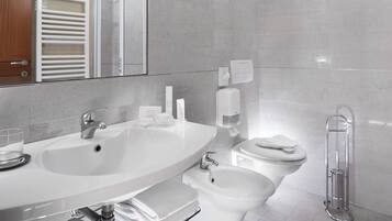 Ein modernes Badezimmer mit einem großen Waschbecken, Toilette, Bidet und einem Spiegel.