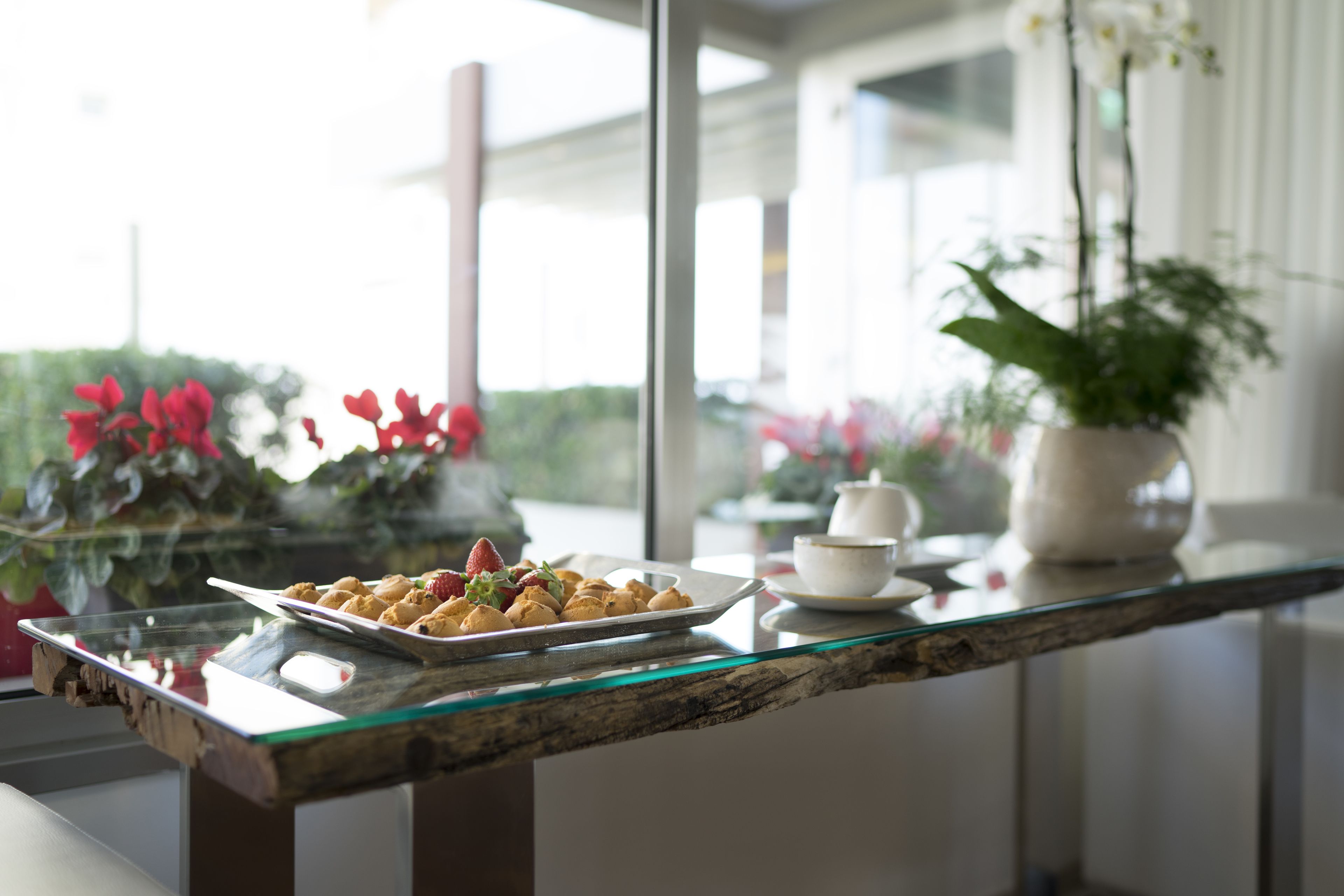 A glass-top table with a plate of pastries and a cup of coffee.