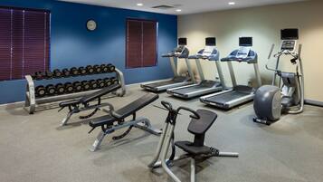 A gym with treadmills, elliptical machines, a bench press, and dumbbells.