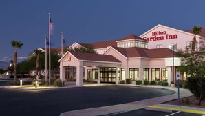 Un Hilton Garden Inn con entrada despejada, palos de señalizaci ón y estacionamiento.