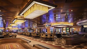 Un casino con varias mesas de juego, máquinas tragamonedas y una ruleta grande.