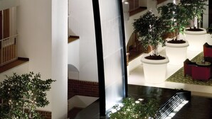 Un vestíbulo de hotel con una fuente central, varios pisos con balcones y plantas en macetas.