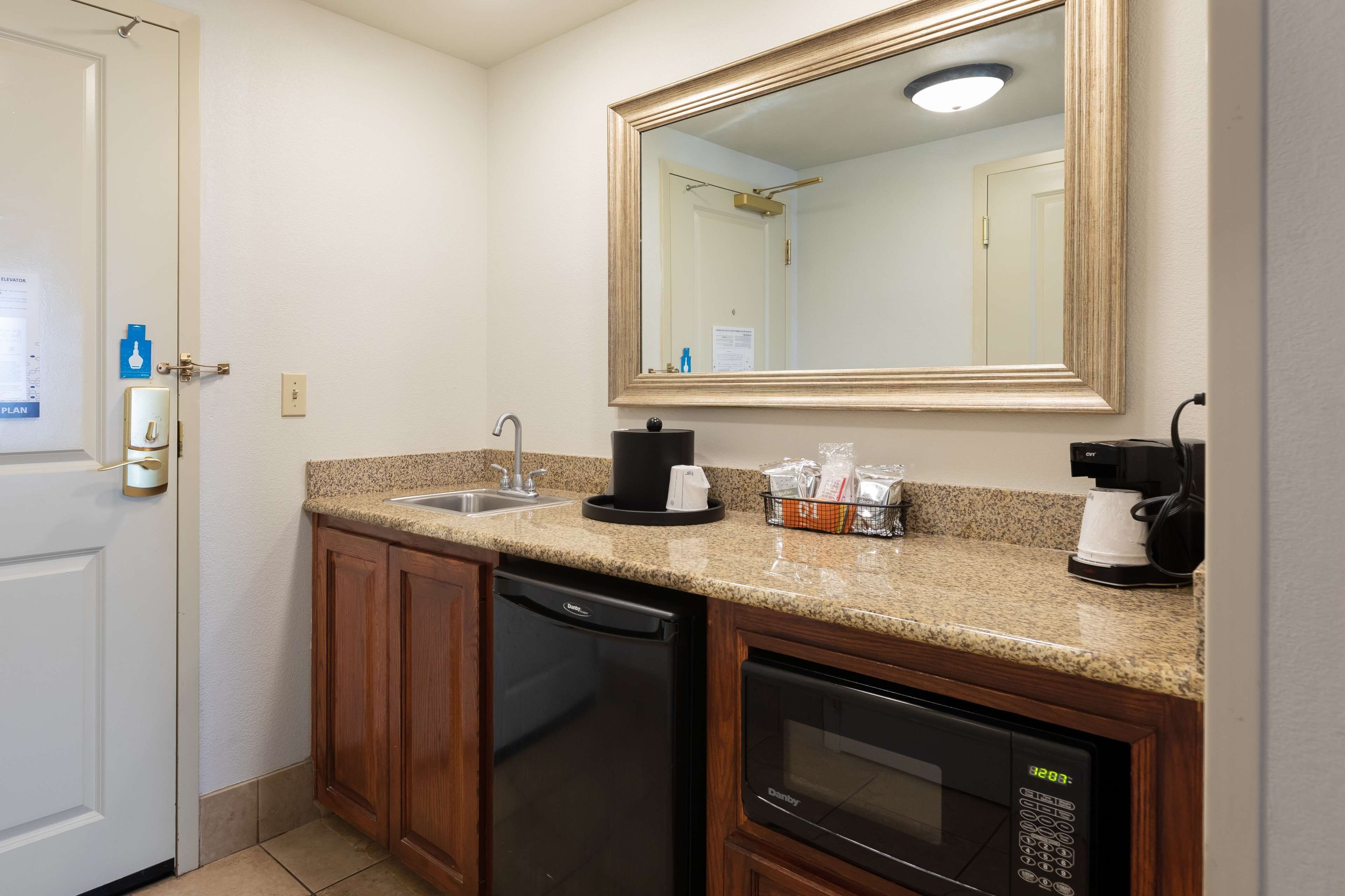 A compact kitchen with a dishwasher, microwave, coffee maker, and a sink.