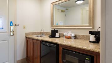 A compact kitchen with a dishwasher, microwave, coffee maker, and a sink.