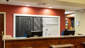 A reception desk with a 'PARKING' sign, a 'GALLERY' sign, and a 'explore.' sign. - Hampton Inn & Suites Baton Rouge - I-10 East (Baton Rouge)