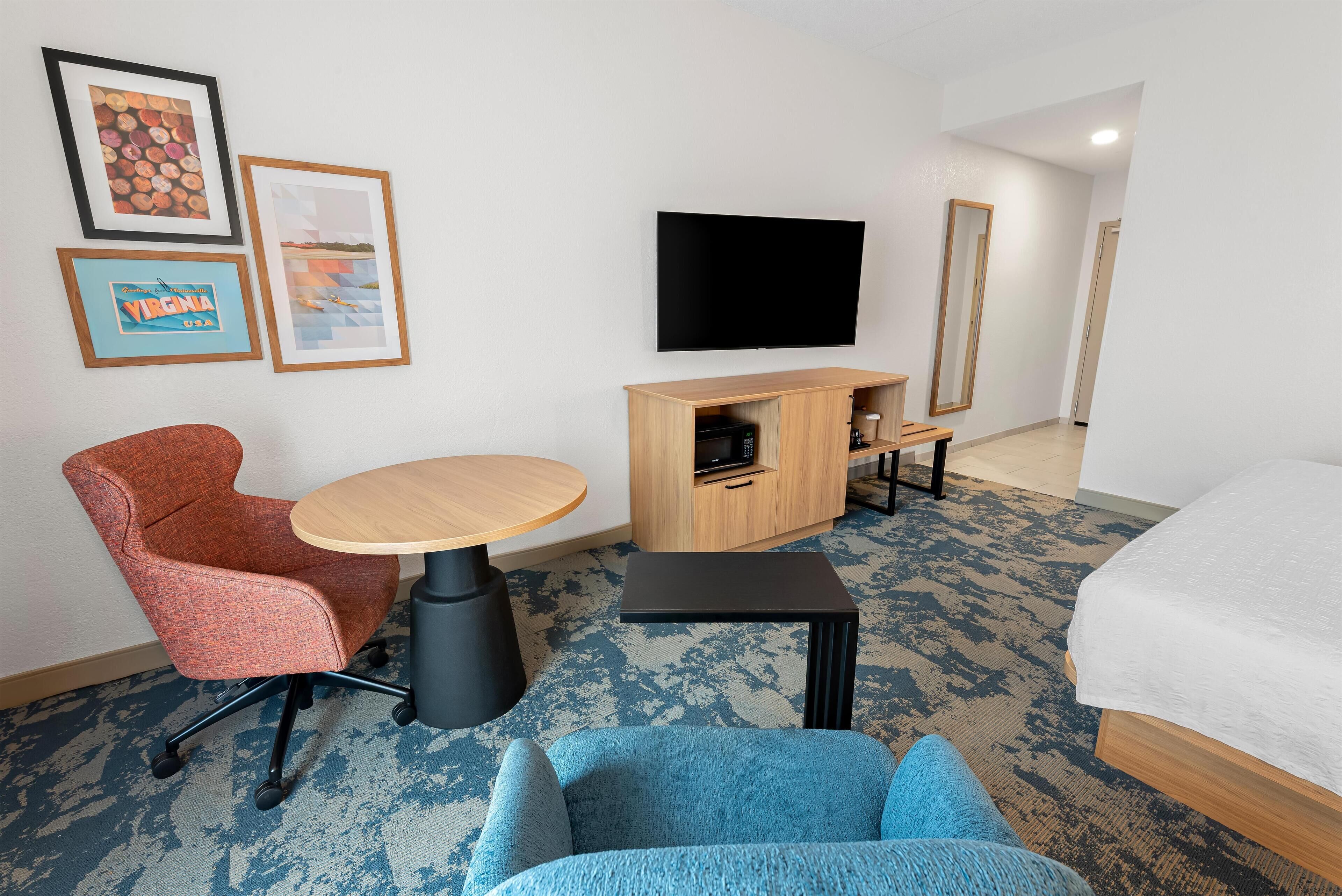 Une chambre d’hôtel équipée d’un lit, d’un bureau, d’une chaise, d’une télévision et d’un four à micro-ondes.