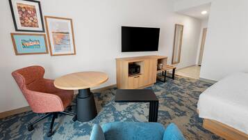 Une chambre d’hôtel équipée d’un lit, d’un bureau, d’une chaise, d’une télévision et d’un four à micro-ondes.